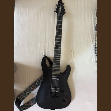 Černá elektrická kytara s matným povrchem a šesti strunami. Na hlavě hmatníku je bílý nápis Jackson. Nástroj má dva humbuckery, jeden ovládací knoflí…