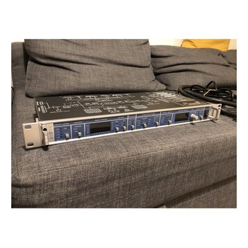 Stříbrné rackové zařízení s černým horním panelem, na kterém je schéma zapojení. Na předním panelu jsou nápisy INPUT LEVEL, LIMITER, INPUT STATE, MET…