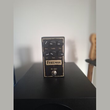 Kytarový efekt pedál v černém kovovém šasi s vypálenými okraji. Na přední straně jsou šest ovládacích knoflíků s popisky Bass, Treble, Pres, Vol, Gai…