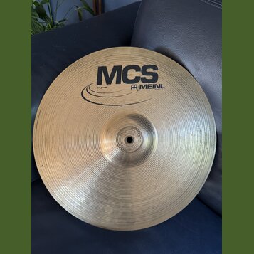 Kruhový mosazný činel s viditelným rýhováním povrchu. Na horní straně je černý nápis MCS a logo MEINL s doplňujícím textem 1953 AND MUSIC. Vlevo od l…