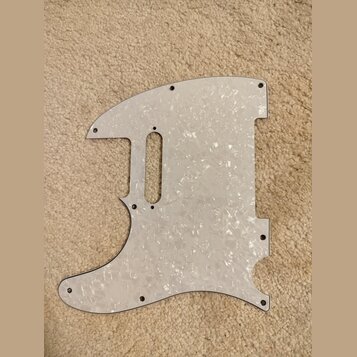 Bílá pickguard s perleťovým vzorem pro elektrickou kytaru. Je vyrobena z plastového materiálu a obsahuje výřezy pro snímače a ovládací prvky. Povrch…