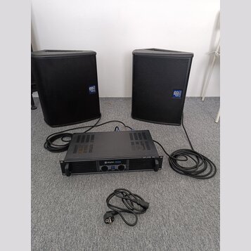 Dva černé reproduktory s mřížkami a modrými logy „dB Technologies“. Mezi nimi je umístěn černý rackový zesilovač s nápisem „skytec PRO244“ a „AMPLIFI…