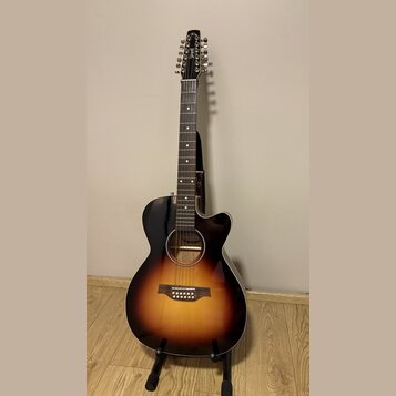 Akustická kytara s 12 strunami v černé barvě s přechodem do oranžové a žluté (sunburst). Na hlavě hmatníku je bílé logo s nápisem "Cort". Nástroj je…
