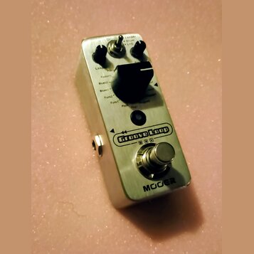 Stříbrný kytarový pedál s nápisem Groove Loop a značkou MOER. Na horní straně jsou dva černé otočné knoflíky, přepínač s nápisy Looper, Drum a L+D or…