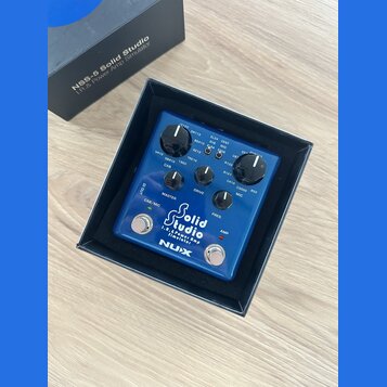Modrý efekt pedál značky NUX s nápisem Solid Studio I.R. & Power Amp Simulator. Zařízení má tři ovládací knoflíky s popisky MASTER, DRIVE a PRES., př…