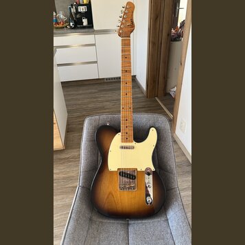 Elektrická kytara s tónem sunburst, krčkem a hmatníkem z přírodního dřeva. Na hlavě je viditelné logo Fender. Kytara má krémový pickguard a chromovan…
