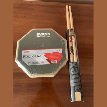 Na fotografii je v originálním balení cvičný pad značky EVANS s nápisem REALFEEL a MOUNTABLE PRACTICE PAD. Pad má šestiúhelníkový tvar, šedý povrch a…