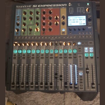Digitální mixážní pult šedé barvy s nápisem Soundcraft SI EXPRESSION. Horní část obsahuje barevně rozdělené sekce s ovládacími knoflíky v modré, zele…