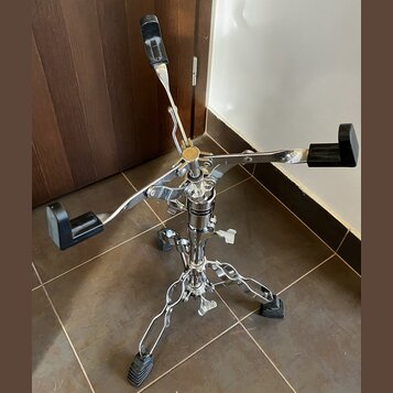 Chromovaný stojan na nástroje s čtyřramennou horní částí a černými gumovými oporami. Na středním sloupku je viditelný nápis "HAMMOND". Stojan stojí n…