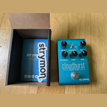 Modrý efekt pedál s nápisem cloudburst a podtitulem ambient reverb. Na spodní části je logo strymon. Pedál má šest ovládacích knoflíků s popisky DECA…