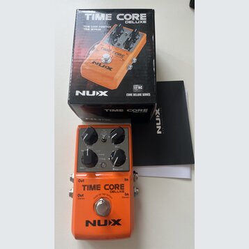 Oranžový efekt pedál s nápisy TIME CORE DELUXE a NUX. Na horní části jsou čtyři černé ovládací knoflíky s popisky Tap/T Lock/Normal, Mix, Time a Repe…