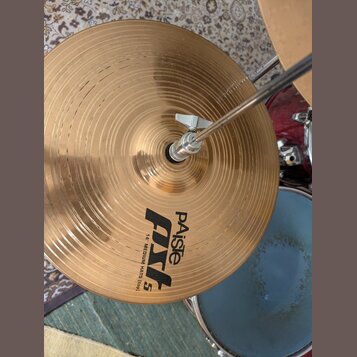 Zlatý kovový činel s koncentrickými drážkami, který je upevněn na stojanu pomocí motýlkového šroubu. Na povrchu je černý nápis „Paiste PSL 5“ a pod n…