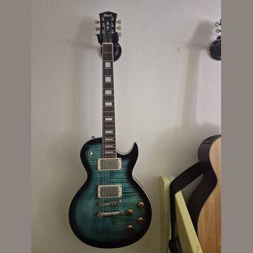 Elektrická kytara s tmavě zeleným gradientem a viditelnou strukturou dřeva. Na hlavě je bílý nápis Cort. Nástroj má dva humbuckery, čtyři otočné knof…