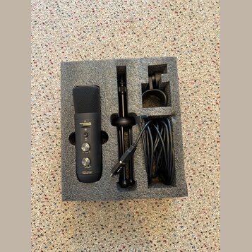Černý mikrofon s mřížkou, na kterém je nápis marantz Professional a v dolní části označení MPM-1000U PODCAST MIC. Součástí sady je černý stolní stati…