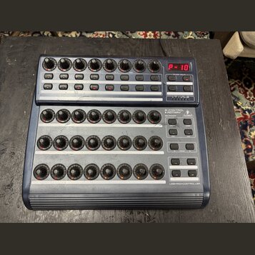 Modrý USB MIDI kontrolér s třemi řadami otočných knoflíků a řadou tlačítek. Na horním panelu je červený digitální displej s nápisem P-10 a nápisy VAL…