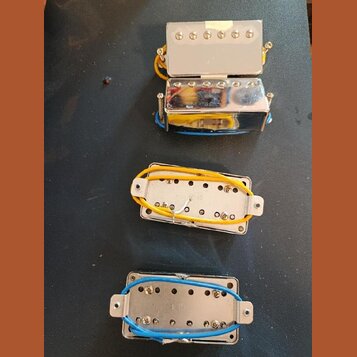 Fotografie zobrazuje čtyři elektrické snímače pro kytaru v chromovaných krytech. Dva snímače jsou zobrazeny z horní strany a dva z rubu, kde jsou vid…