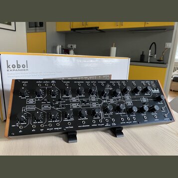 Černý analogový semi-modulární syntetizátor s nápisem kobol EXPANDER. Přední panel obsahuje zahlreiche ovládací knofíky, přepínače a zapojovací konek…