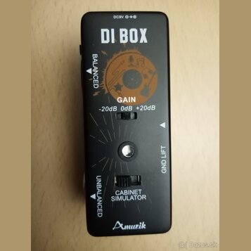Černý DI box s nápisem DI BOX a logem Amuzik v dolní části. Zařízení obsahuje přepínače GAIN s hodnotami -20dB, 0dB, +20dB a CABINET SIMULATOR, dále…