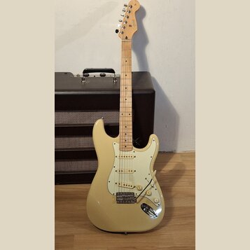 Krémová elektrická kytara typu Stratocaster s bílým pickguardem a javorovým hmatníkem. Na hlavě je viditelné logo Squier. Kytara je umístěna před čer…