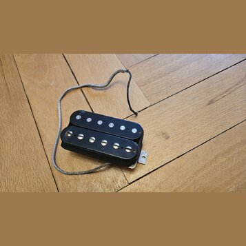 Černý humbucker s dvěma řadami bílých magnetických pólců. Nástroj nemá žádné viditelné značky ani nápisy. K pickupu vede stříbrně opletený kabel.