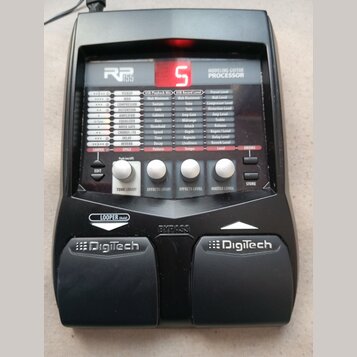 Černý kytarový procesor s nápisem RP 155 MODELING GUITAR PROCESSOR. Zařízení má digitální displej s červeným číslem 5, několik ovládacích tlačítek a…