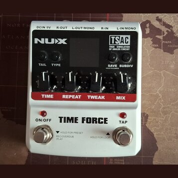 Bílý kytarový efekt s černým ovládacím panelem a červenými popisky. Na panelu jsou nápisy NUX, TSAC TRUE SIMULATION OF ANALOG CIRCUIT a TIME FORCE. J…