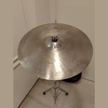 Stříbrný kovový činel umístěný na chromovaném stojanu. Na povrchu je viditelný nápis Zildjian a v horní části menší nápis K. Povrch vykazuje jemné šk…