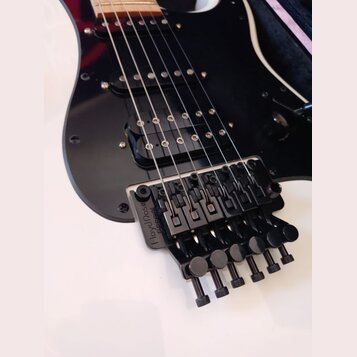 Černá elektrická kytara s černým pickguardem a humbuckerem v pozici u mostu. Nástroj je vybaven černým plovoucím mostem s nápisem Floyd Rose Special.…