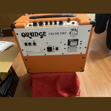 Zadní strana oranžového kytarového komba s bílým zadním panelem. Na panelu je nápis ORANGE CRUSH 35RT a logo značky Orange. Jsou zde vidět ovládací p…
