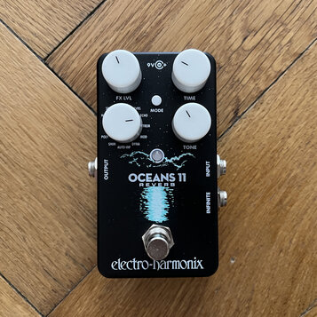 Černý efekt pedál s bílými ovládacími knoflíky. Na zařízení jsou nápisy FX LVL, TIME, MODE, TONE a v dolní části logo electro-harmonix. Uprostřed je…