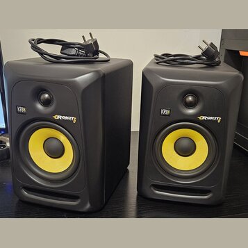 Dva černé studiové monitory s žlutými membránami basových reproduktorů. Na přední straně každého reproduktoru je logo KRK a nápis ROKIT 6. K oběma př…