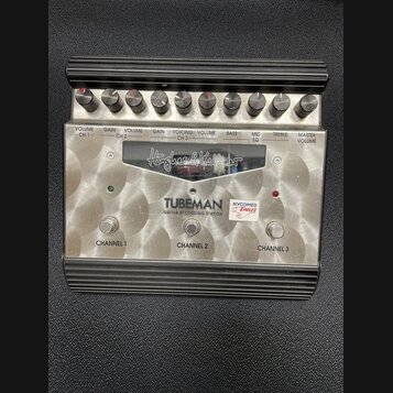 Stříbrný kytarový předzesilovač s černým žebrovaným rámem. Na čelním panelu je nápis „Hughes & Kettner“, modelové označení „TUBEMAN GUITAR RECORDING…