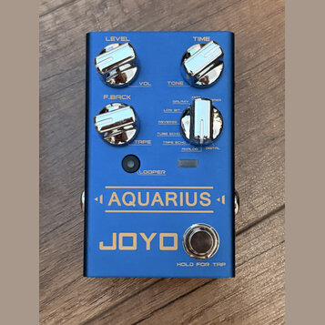 Modrý efekt pedál s nápisy AQUARIUS a JOYO. Na horní části jsou čtyři chromované ovládací knoflíky s popisky LEVEL, TIME, F.BACK a TAPE. U pravého kn…