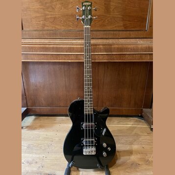 Černý elektrický basový kytara s tmavým hmatníkem. Na hlavě je zlatý nápis GRETSCH a na korpusu v pravé dolní části bílý nápis GRETSCH. Nástroj má dv…