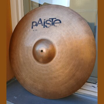 Kovový činel v bronzové barvě s viditelným koncentrickým rýhováním povrchu. V horní části je modré logo pAiste a pod ním menší nápis 20 RIDE. Povrch…