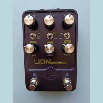 Tmavě hnědý kytarový pedál s nápisem LION 68 SUPER LEAD AMP a logem UA v kosočtverci. Horní řada obsahuje tři otočné knoflíky s popisky VOLUME I, VOL…