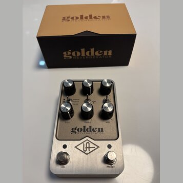 Kytarový efekt v kovovém šasi stříbrné barvy s nápisem golden REVERBERATOR a logem UA. Pedal má šest černých otočných knoflíků s označením BASS, TREB…
