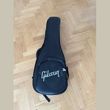 Černý polotvrdý pouzdro na kytaru z umělé kůže. Na spodní části je bílý nápis Gibson. Povrch vykazuje mírné známky opotřebení a vrásnění materiálu.