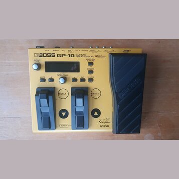 Žlutý kytarový procesor BOSS GP-10 GUITAR PROCESSOR s černým expresním pedálem. Zařízení má dvě černé spínací tlačítka, displej a několik ovládacích…