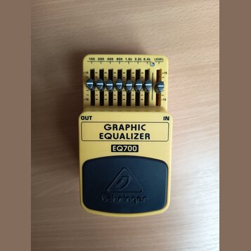 Žlutý kytarový pedál s černým horním panelem. Na černém panelu je logo a nápis behringer, níže je uveden model EQ700 a text GRAPHIC EQUALIZER. Zaříze…