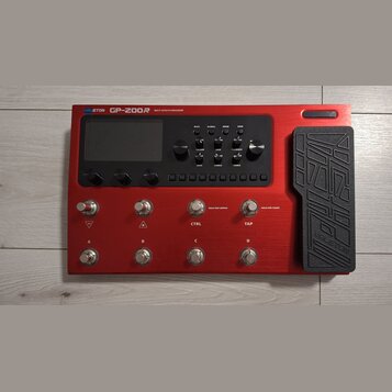 Červený kytarový procesor s nápisem VALETON GP-200R MULTI-EFFECTS PROCESSOR. Zařízení má displej, několik ovládacích knoflíků a řadu tlačítek. V doln…