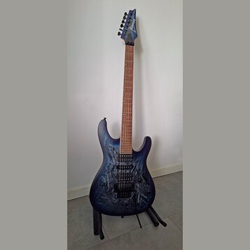 Elektrická kytara s modrým průsvitným povrchem a viditnou strukturou dřeva. Na hlavě hmatníku je bílý nápis Ibanez. Nástroj má dva humbuckery, jeden…