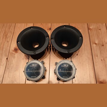 Dva černé tubové reproduktory s kruhovým hornem a čtyři montážními otvory. Pod nimi jsou dva magnetické členy s nápisy SICA loudspeakers a MADE IN IT…