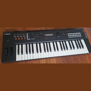 Černý klavírní syntetizátor s bílými a černými klávesami. Na levé straně je nápis YAMAHA a na pravém okraku svisle napsáno 64xw. V horní části panelu…