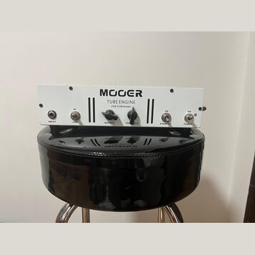 Bílý kytarový koncový zesilovač s nápisy MOOER, TUBE ENGINE a 20W POWERAMP. Přední panel obsahuje vstup INPUT, přepínač HI/LOW, otočný ovladač MASTER…