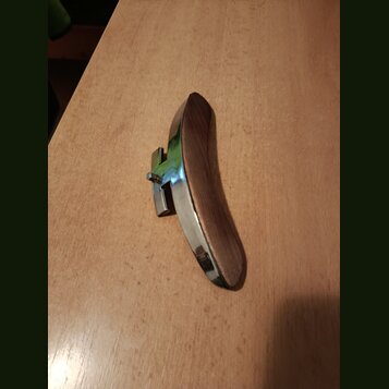 Na fotografii je zobrazen kovový a dřevěný předmět, pravděpodobně opěrka na violinčel nebo kontrabas. Předmět má zakřivený tvar s kovovým povrchem a…