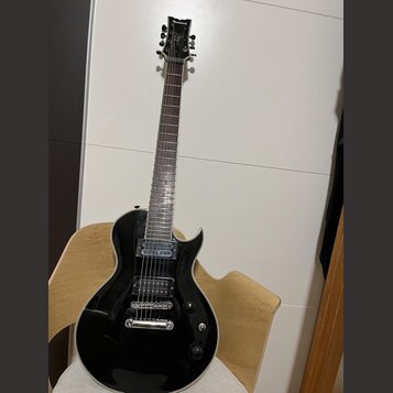 Černá elektrická kytara s dvojstupňovými humbuckery a bílým lemováním těla. Na hlavě je nápis "banez" a logo "Banez". Nástroj vykazuje mírné opotřebe…
