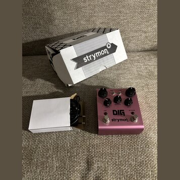 Růžový efekt pedál s nápisy DIG dual digital delay a strymon. Na horní straně jsou čtyři černé ovládací knoflíky, dva spínače s nápisy TAP a BYPASS a…