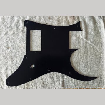 Černý plastový pickguard pro elektrickou kytaru s výřezem pro ovladače a otvorem pro kabel. Povrch je hladký a bez viditelných značek, log nebo nápis…