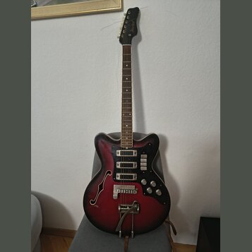 Elektrická kytara s polodupatým korpusem v červeně-černém sunburst provedení. Na hlavě hmatníku je viditelné logo Samick. Nástroj má dva snímače, čty…